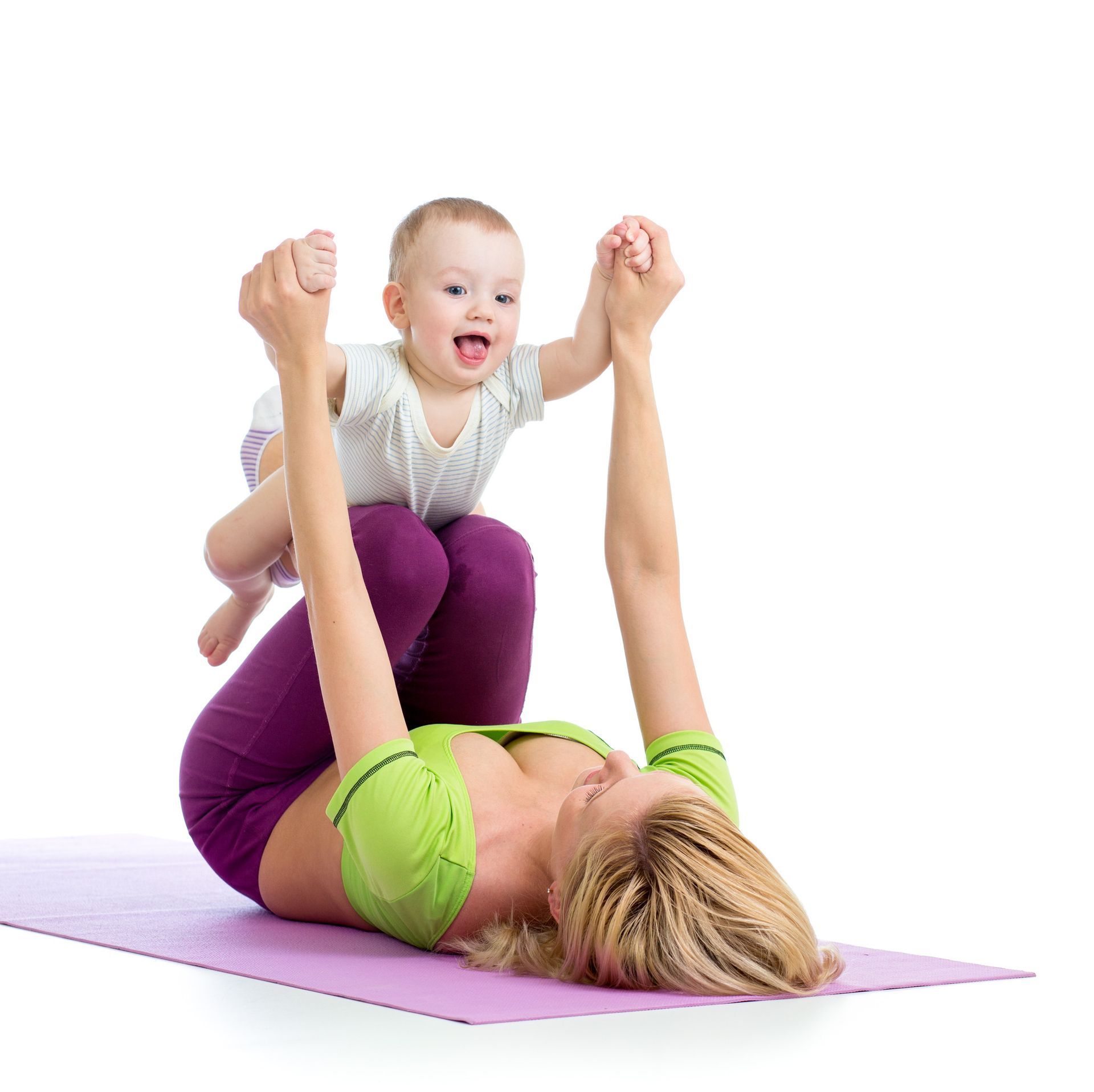 Una mujer está acostada sobre una esterilla de yoga sosteniendo un bebé en sus brazos.